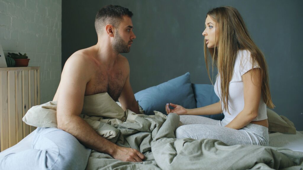 Pareja conversando en la cama sobre su relación